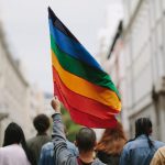 A group of people walking down a street, proudly holding a rainbow flag during a vibrant gay event.