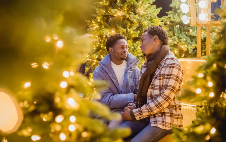 Two people sitting in front of a Christmas tree at local gay events.