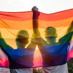 Two men, proud participants of gay events on the Sunshine Coast, are holding up a rainbow flag.