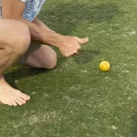 A man crouching down next to a vibrant ball.