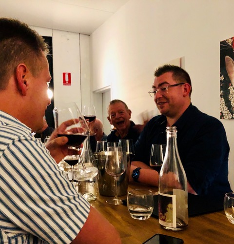 A group of people, including attendees at QAF Tours and Events, sitting around a table drinking wine at one of the local gay pride events this weekend.