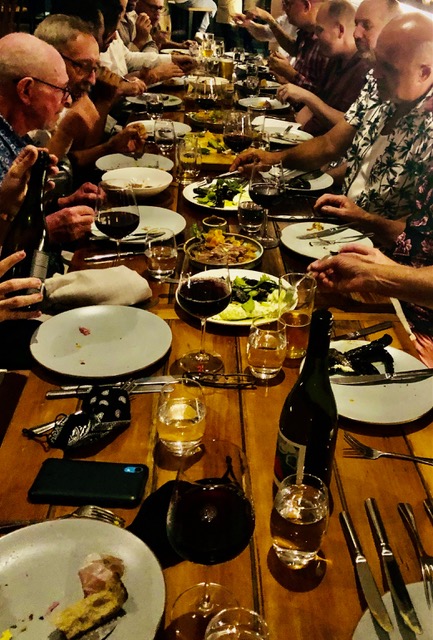 A group of gay people sitting at a long table at one of the gay events this weekend.