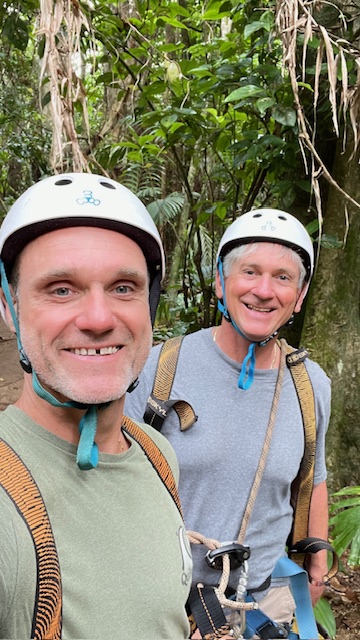 Two men wearing helmets on a hike in the jungle during a gay event.