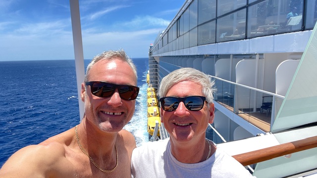 Two men capturing a selfie on the deck of a cruise ship.
