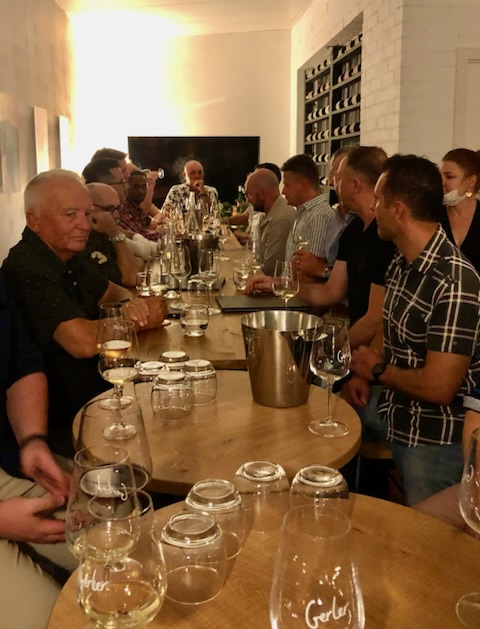 A group of LGBTQ individuals sitting around a table with wine glasses at a local gay pride event.